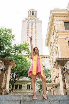 a woman is standing on the steps in front of a building and raising her hand