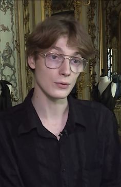 a young man wearing glasses in front of a mirror