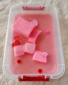 a plastic container filled with pink stuff on top of a white carpet