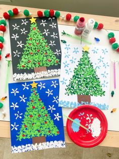 three paper plates with christmas trees on them next to crafting supplies and paintbrushes