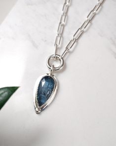 Stunning rose cut teal blue teardrop Kyanite gemstone set in sterling silver with a sterling silver bead design. The Kyanite pendant hangs from a sterling silver paperclip chain and clasp. D E T A I L S . . . . . . . .  Metal: Sterling Silver Gemstone: Kyanite Chain Length: 16", 17", 18" Pendant Dimensions: 30mm x 15mm Handmade jewelry with Love and Passion by Grace Lilly Designs. Handcrafted in the USA. Blue Teardrop Pendant Necklace In Sterling Silver, Blue Sterling Silver Teardrop Pendant Necklace, Sapphire Teardrop Pendant Necklace In Sterling Silver, Silver Gemstone Teardrop Pendant Necklace, Silver Teardrop Pendant Necklace With Gemstone, Sterling Silver Teardrop Necklace With Gemstone Accents, Sterling Silver Teardrop Pendant Necklace With Gemstone, Sapphire Teardrop Jewelry With Gemstone Accents, Sapphire Teardrop Pendant Jewelry