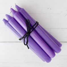 several purple candles tied together on a white table