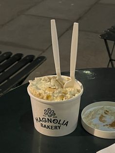 an ice cream sundae with two spoons in it on a table next to a plate