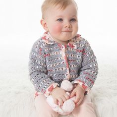 a baby sitting on top of a white blanket holding a stuffed animal in it's hands