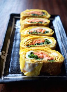 some food is on a black plate with the words tamagoyaki japanese rolled omelettes