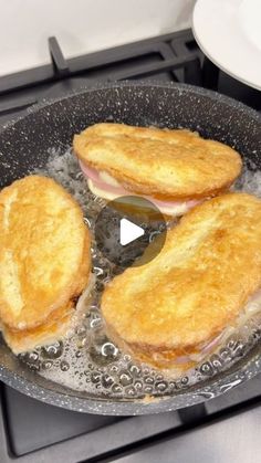 two sandwiches cooking in a frying pan on top of a gas stove with water