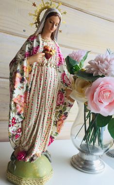 a statue of the virgin mary with flowers in a vase