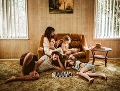 a group of people sitting on top of a couch in a living room next to each other