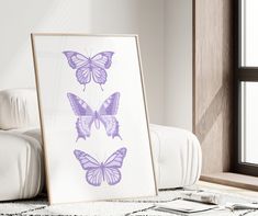 three purple butterflies are displayed in front of a window