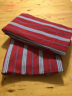 two red and blue striped towels folded on top of each other in front of a wooden table