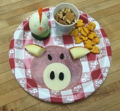 a pig face made out of cheese, crackers and fruit on a red and white plate