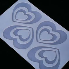 four heart shaped cut outs are shown on a black surface with white paper in the shape of hearts