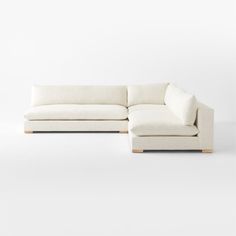 a white sectional couch sitting on top of a white floor next to a wooden frame