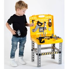 a young boy standing next to a toy work bench