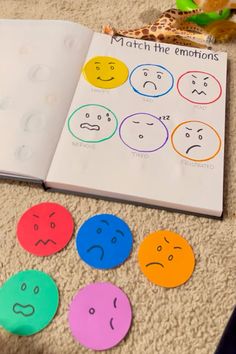 an open book sitting on top of a carpet next to different colored smiley face stickers