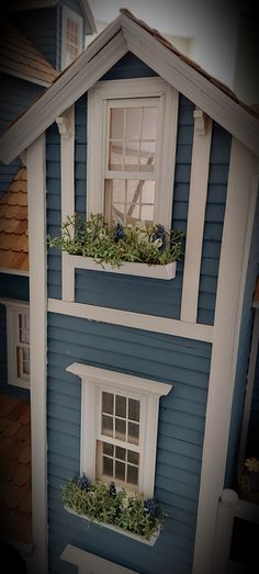 a doll house with blue siding and white windows