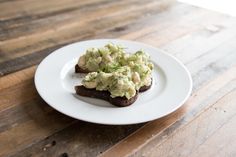 two pieces of toast topped with guacamole on a white plate