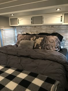 a bed with black and white checkered comforter in a small room next to windows