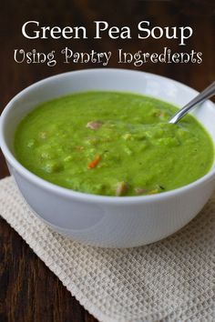 a white bowl filled with green pea soup on top of a wooden table next to a napkin