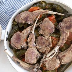 a white bowl filled with meat and vegetables on top of a blue and white table cloth