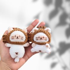 a hand holding two small crocheted stuffed animals