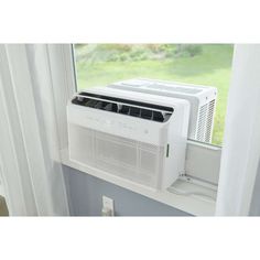 a white air conditioner sitting on top of a window sill