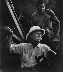 an old black and white photo of a man in a straw hat with another man standing behind him