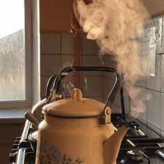 a kettle with steam rising from it sitting on top of a stove