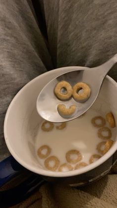 a person holding a spoon with doughnuts in it that are shaped like the letter o