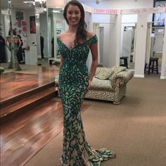 a woman in a green and white dress standing on the floor next to some stairs