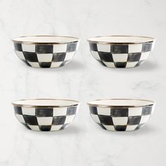 four black and white bowls sitting on top of a marble counter