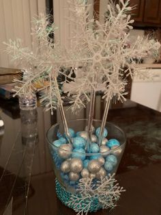 a glass vase filled with blue and silver ornaments on top of a table next to a counter