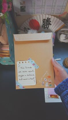 a person holding up a piece of paper with writing on it in front of a fan