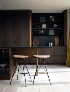 two wooden stools sit in front of a desk