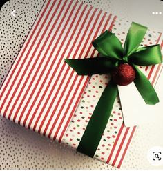 a present wrapped in red and white paper with a green bow on it's side