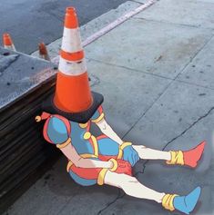 a cartoon character laying on the ground next to an orange cone