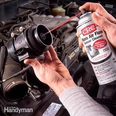 a person is working on an air filter in the hood of a car while holding a spray bottle