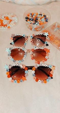 four pairs of sunglasses with flower decorations on them sitting on a table next to candy