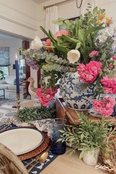 a vase filled with pink and white flowers on top of a wooden table next to a plate