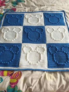 a blue and white crocheted blanket sitting on top of a bed