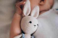 a baby is holding a crocheted bunny toy