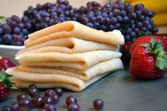 a stack of waffles sitting next to some grapes and strawberries on a table