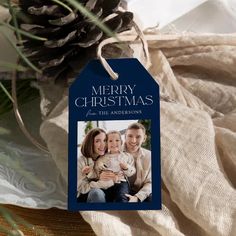 a merry christmas card with a photo and pine cone in the background on a table