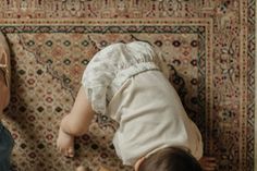 two babies playing with each other in front of a rug