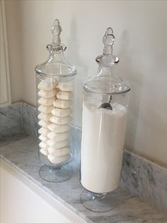 two glass jars filled with marshmallows on top of a counter next to each other