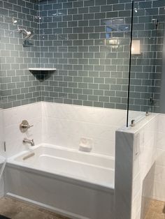 a white bath tub sitting inside of a bathroom next to a tiled wall and floor