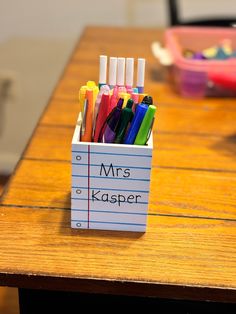 a desk with a pen holder filled with markers and pencils on top of it