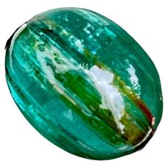 an oval glass object with green and white designs