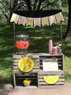 a lemonade stand is set up outside in the grass with some fruit on it