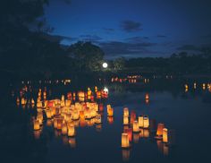 many lanterns floating in the water at night